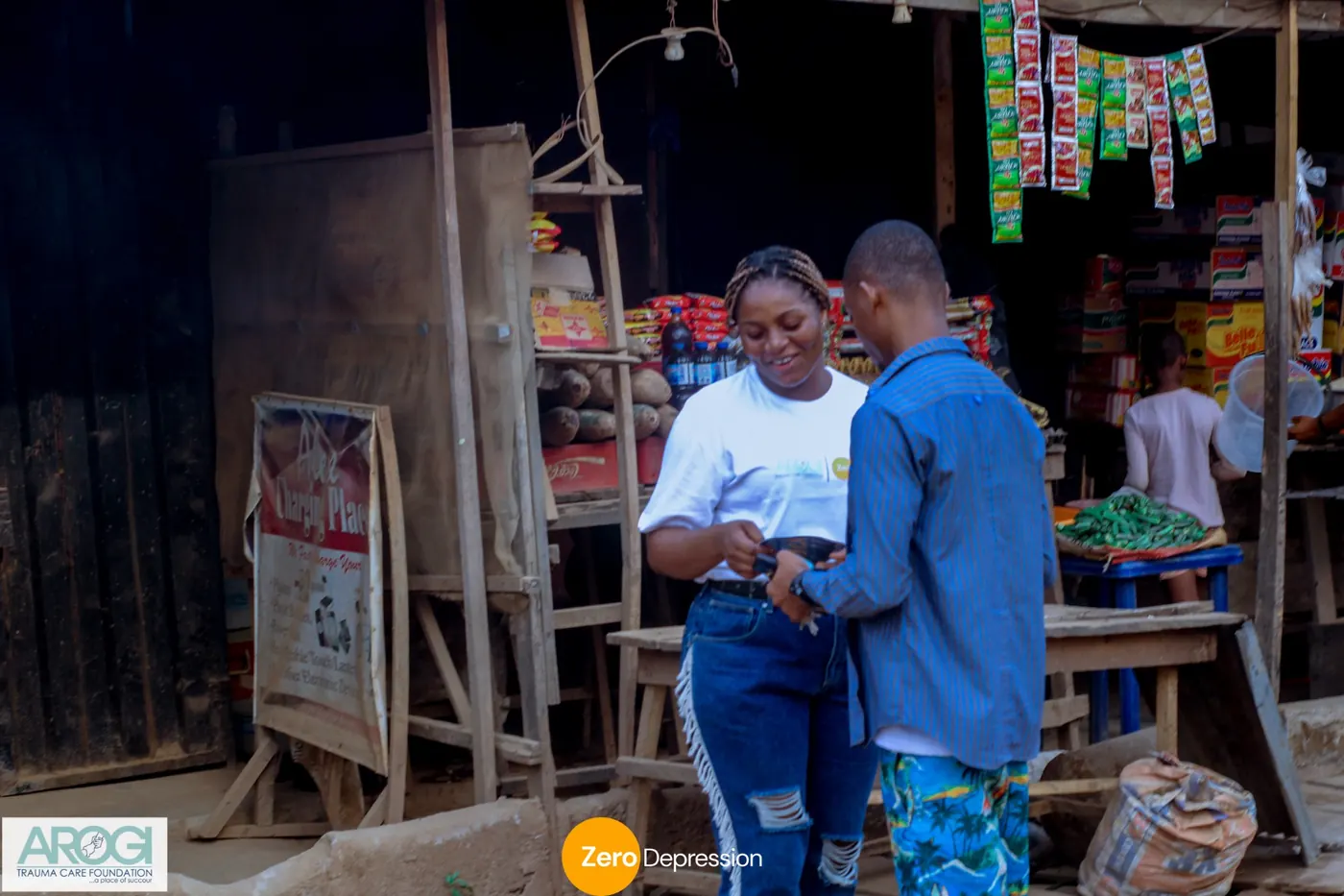 A volunteer handing a flyer to a man outside a small market stall