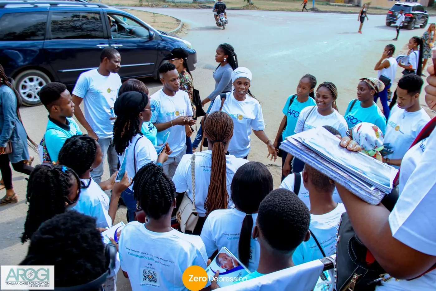 A volunteer addressing a circle of volunteers on the road before heading out with flyers