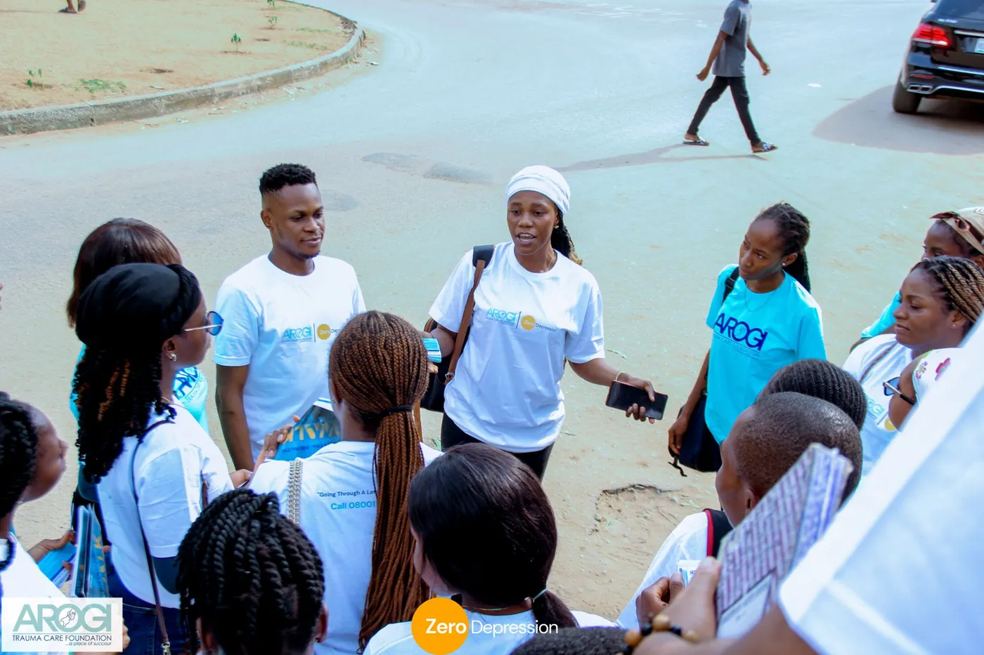 A ZeroDepression volunteer in a white t-shirt speaking to a group of volunteers during an outreach on the street